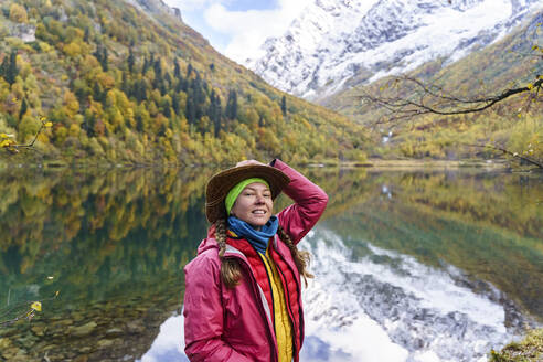 Frau vor einem Berg stehend, der sich in einem See spiegelt, Kaukasus-Naturschutzgebiet, Sotschi, Russland - OMIF00607