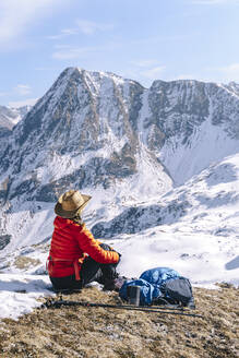 Frau in warmer Kleidung mit Blick auf einen schneebedeckten Berg, Naturschutzgebiet Kaukasus, Sotschi, Russland - OMIF00609