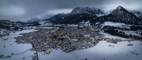 Deutschland, Bayern, Oberstdorf, Hubschrauberpanorama der verschneiten Stadt in den Allgäuer Alpen in der Abenddämmerung - AMF09389