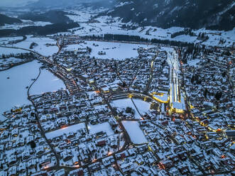 Deutschland, Bayern, Oberstdorf, Blick aus dem Hubschrauber auf die schneebedeckte Stadt in den Allgäuer Alpen in der Abenddämmerung - AMF09390