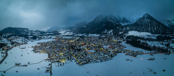 Germany, Bavaria, Oberstdorf, Helicopter panorama of snow covered town in Allgau Alps at dusk - AMF09391