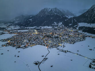 Deutschland, Bayern, Oberstdorf, Blick aus dem Hubschrauber auf die schneebedeckte Stadt in den Allgäuer Alpen in der Abenddämmerung - AMF09392