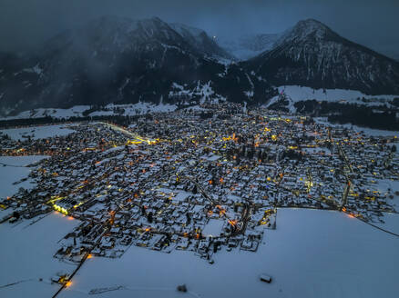 Deutschland, Bayern, Oberstdorf, Blick aus dem Hubschrauber auf die schneebedeckte Stadt in den Allgäuer Alpen in der Abenddämmerung - AMF09393