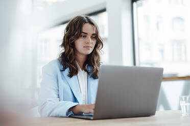 Beautiful businesswoman working on laptop in office - GUSF06774