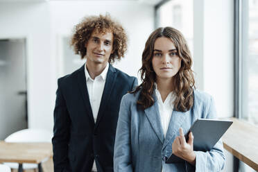 Young businesswoman with tablet PC standing in front of businessman in office - GUSF06794