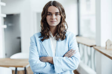 Confident businesswoman standing with arms crossed in office - GUSF06823