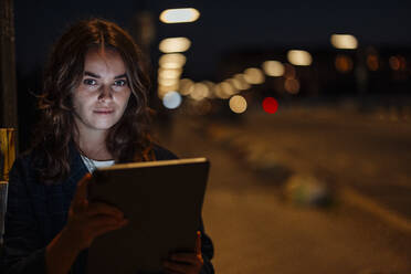 Schöne Frau mit Tablet-PC auf der Straße in der Stadt bei Nacht - GUSF06856