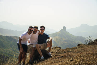 Glückliche junge Freunde sitzen auf einem Felsen in Degollada de Becerra, Spanien - RSGF00858