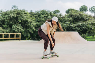 Junge Frau fährt Skateboard auf einer Sportrampe - JRVF02738