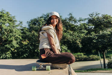 Lächelnde Frau auf Skateboard im Park - JRVF02749