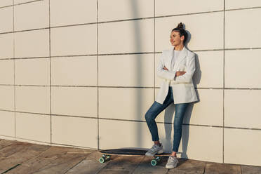Frau mit Skateboard nachdenklich auf Gehweg - JRVF02769