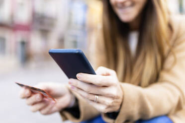 Woman with debit card making online payment through smart phone - XLGF02659