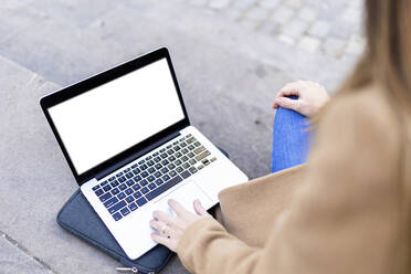 Frau benutzt Laptop auf dem Fußweg - XLGF02664