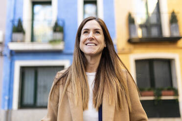 Lächelnde Frau mit langen braunen Haaren in der Stadt - XLGF02667