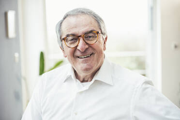 Happy senior man with gray hair wearing eyeglasses at home - UUF25333