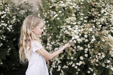 Blondes Mädchen berührt weiße Blumen - ANF00013