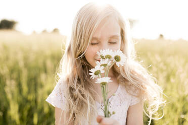Blondes Mädchen riecht an frischen Blumen im Feld - ANF00022