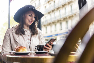 Lächelnde Frau mit Mobiltelefon in einem Café - WPEF05802