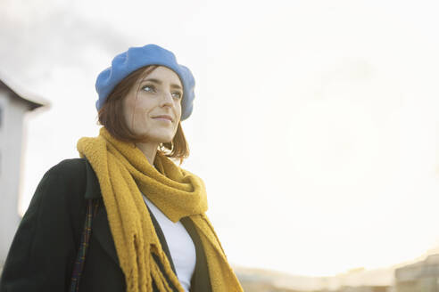 Schöne Frau mit blauer Baskenmütze und gelbem Schal an einem sonnigen Tag - MTBF01146