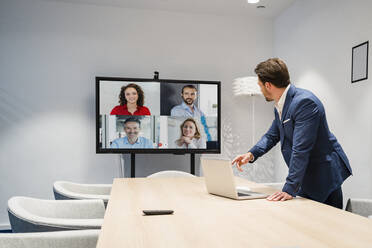 Geschäftsleute, die in einer Sitzung über eine Webkonferenz im Büro diskutieren - DIGF17421