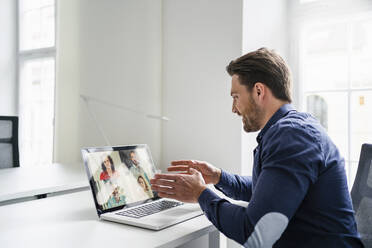 Geschäftsmann bespricht Ideen mit Kollegen per Videoanruf über einen Laptop im Büro - DIGF17438