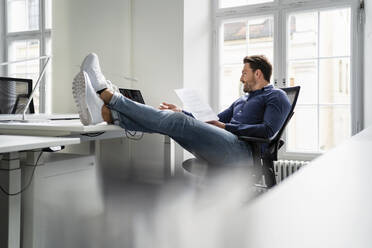 Businessman working on laptop at desk in office - DIGF17439