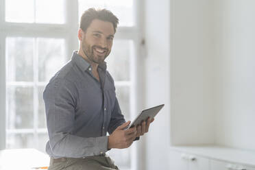 Smiling businessman with tablet PC in office - DIGF17470