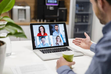 Businessman discussing with colleagues on video call at home office - DIGF17473