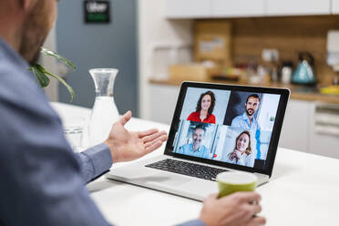 Businessman discussing with colleagues in web conference at home office - DIGF17474