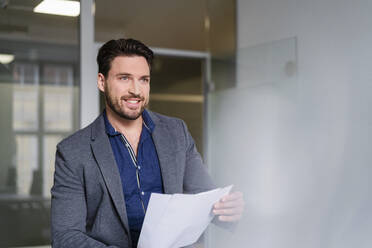 Businessman with document contemplating in office - DIGF17491