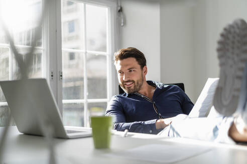 Geschäftsmann mit Dokument und Laptop im Büro - DIGF17522