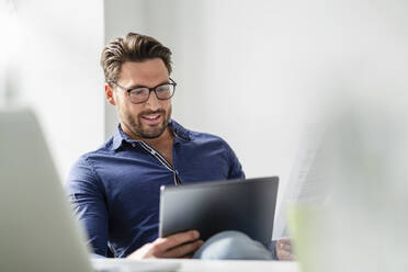 Geschäftsmann mit Brille und Tablet-PC im Büro - DIGF17530