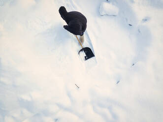Frau beim Schneeräumen mit Schneeschaufel im Winter - KNTF06599