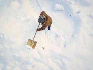 Mann beim Schneeräumen mit Schneeschaufel im Winter - KNTF06600