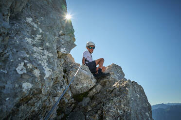 Junge sitzt auf einem Felsen an einem sonnigen Tag - DIKF00595