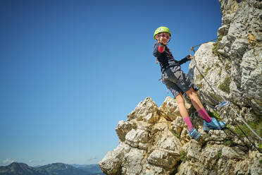 Mädchen, das auf einem Felsen stehend den Daumen nach oben streckt - DIKF00597