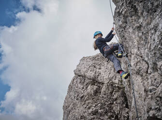 Smiling girl climbing rocky mountain - DIKF00611