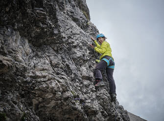 Lächelnde Frau klettert auf felsigen Berg - DIKF00613