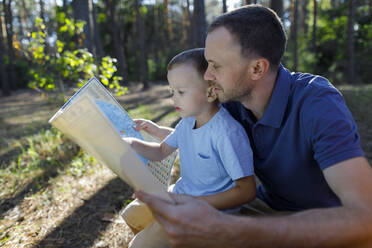 Father and son reading map in forest - TYF00070