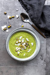 Studio shot of bowl of vegan pea soup with zucchini, broccoli, pistachios and coconut shreds - SARF04675
