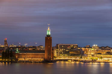 Sweden, Stockholm County, Stockholm, Skyline of Riddarholmen at dusk with Stockholm City Hall in foreground - FOF12863