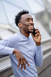 Happy man with black hair talking on smart phone - OCMF02325