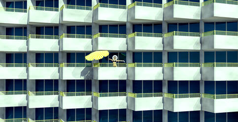 Frau im Bikini steht mit ausgestreckten Armen auf einem Balkon an einem sonnigen Tag - VTF00657