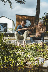 Lächelnder Vater und Sohn geben sich einen Faustschlag, während sie auf den Stufen im Hinterhof sitzen - GUSF06928