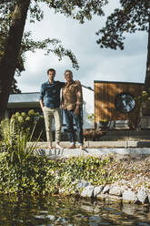 Man with hand in pocket standing with father on steps at backyard - GUSF06930