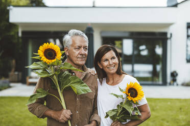 Paar mit Sonnenblumen im Hinterhof stehend - GUSF06958