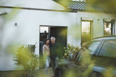 Älterer Mann mit Frau vor dem Haus stehend mit Auto - GUSF06991