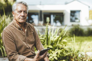 Älterer Mann mit Tablet-PC im Hinterhof sitzend - GUSF07014