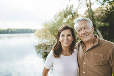Lächelnder älterer Mann mit Frau am See stehend - GUSF07051