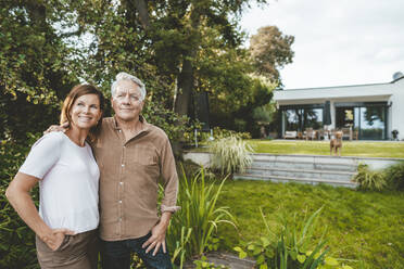 Smiling woman with brown hair standing by man at backyard - GUSF07057